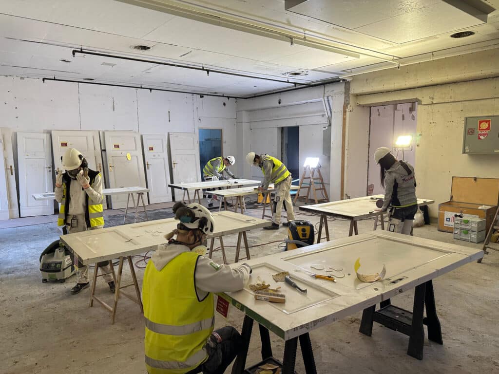 Restaurering av originale dører i teaterbygget. Arbeidet inngår som en del av moderniseringen, der eksisterende materialer og historiske elementer tas vare på og settes i stand for videre bruk.